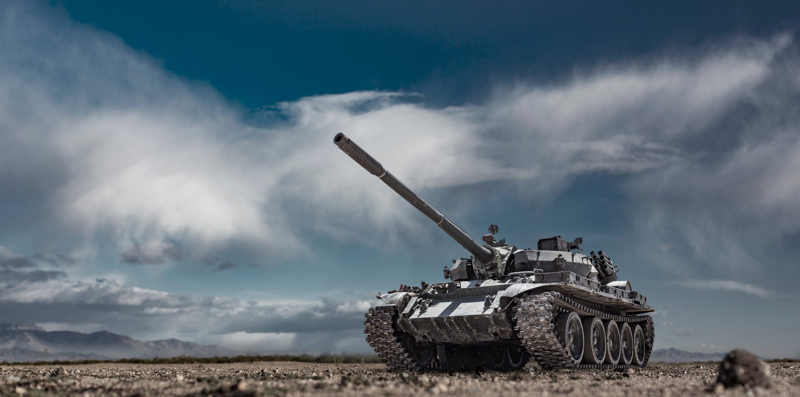 Military or army tank ready to attack moving over a deserted battle field terrain